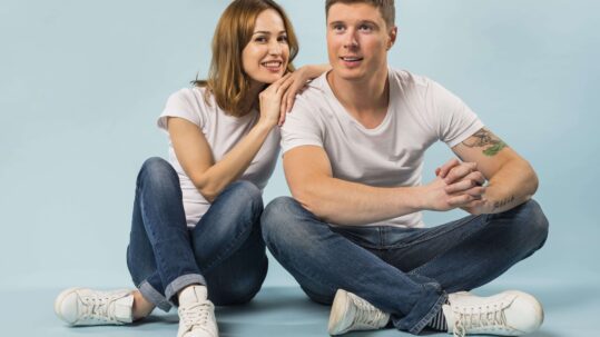 smiling-young-woman-sitting-her-boyfriend-against-blue-background (1) (1)